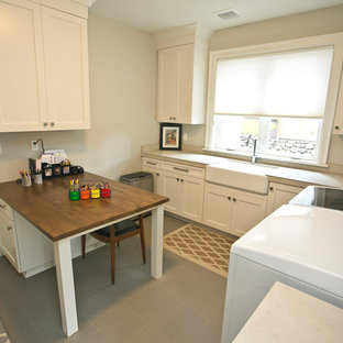 Inspiration for a medium sized traditional utility room in Portland with a belfast sink, shaker cabinets, white cabinets, tile countertops, beige walls, ceramic flooring, a side by side washer and dryer and grey floors.