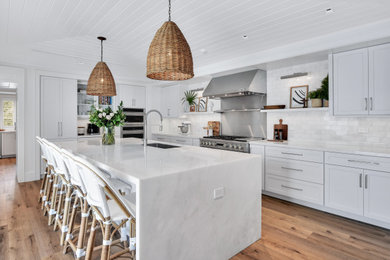 Inspiration for a large coastal u-shaped medium tone wood floor, brown floor and shiplap ceiling enclosed kitchen remodel in Miami with an undermount sink, shaker cabinets, white cabinets, marble countertops, white backsplash, subway tile backsplash, stainless steel appliances, an island and white countertops