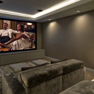 Photo of a large contemporary enclosed home cinema in Kent with brown walls, carpet, a projector screen and beige floors.