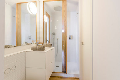 Design ideas for a mid-sized scandinavian master bathroom in Barcelona with flat-panel cabinets, white cabinets, a curbless shower, a wall-mount toilet, white tile, ceramic tile, white walls, light hardwood floors, an undermount sink, solid surface benchtops, beige floor and a hinged shower door.