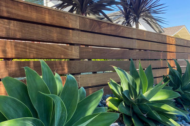 Diseño de jardín de secano en patio delantero con camino de entrada, piedra decorativa y con madera