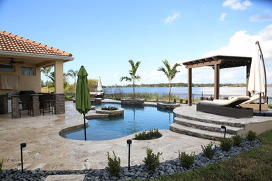 Photo of a large tropical backyard custom-shaped pool in Orlando with a hot tub and tile.
