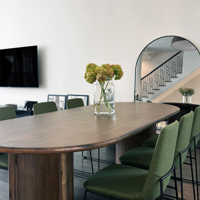 This dining area radiates timeless elegance with a modern edge. The centerpiece is a custom-crafted wooden dining table, seamlessly paired with plush green chairs that bring a refreshing pop of color.