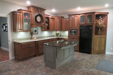 Eat-in kitchen - mid-sized traditional l-shaped ceramic tile eat-in kitchen idea in Other with raised-panel cabinets, medium tone wood cabinets, granite countertops, green backsplash, black appliances and an island