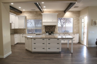 Mid-sized elegant l-shaped medium tone wood floor and brown floor enclosed kitchen photo in Las Vegas with an undermount sink, shaker cabinets, white cabinets, granite countertops, multicolored backsplash, subway tile backsplash, an island and beige countertops