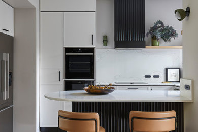Photo of a small contemporary u-shaped kitchen pantry in Melbourne with recessed-panel cabinets, white cabinets, quartz benchtops, engineered quartz splashback, black appliances, a peninsula, brown floor and white benchtop.