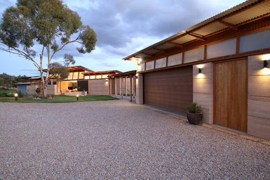 This is an example of a large modern one-storey house exterior in Central Coast with stone veneer, a flat roof and a metal roof.