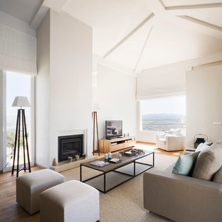 Imagen de salón para visitas abierto, mediterráneo, de tamaño medio, con paredes blancas, suelo de madera en tonos medios, chimenea tradicional y pared multimedia