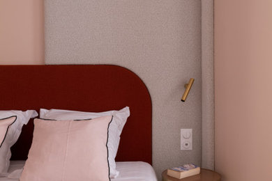 Diseño de dormitorio principal actual de tamaño medio con paredes rosas, suelo de madera clara, suelo marrón y papel pintado