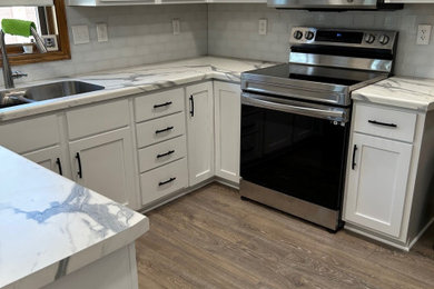 Mid-sized minimalist u-shaped eat-in kitchen photo in Other with white cabinets, laminate countertops, white backsplash and glass tile backsplash