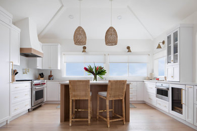 Large nautical u-shaped kitchen/diner in San Francisco with a submerged sink, shaker cabinets, white cabinets, engineered stone countertops, white splashback, engineered quartz splashback, coloured appliances, light hardwood flooring, an island, brown floors, white worktops and a vaulted ceiling.