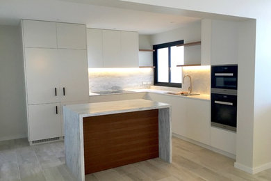 Mid-sized contemporary l-shaped eat-in kitchen in Sydney with a drop-in sink, flat-panel cabinets, medium wood cabinets, marble benchtops, multi-coloured splashback, marble splashback, panelled appliances, travertine floors, with island and beige floor.