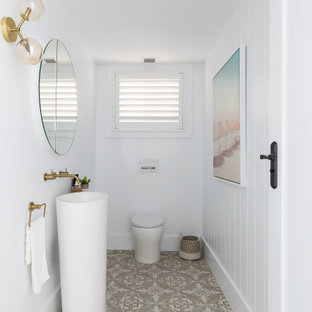 Design ideas for a mid-sized beach style bathroom in Sydney with white cabinets, a wall-mount toilet, white walls, ceramic floors, a pedestal sink, beige floor, an enclosed toilet, a single vanity, a freestanding vanity and planked wall panelling.