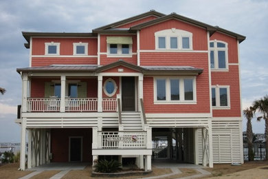 Example of a large beach style orange two-story concrete fiberboard house exterior design in Other with a hip roof and a metal roof