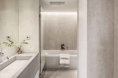 Inspiration for a medium sized modern grey and white ensuite bathroom in Barcelona with freestanding cabinets, grey cabinets, a built-in bath, a walk-in shower, a wall mounted toilet, grey tiles, stone slabs, grey walls, limestone flooring, a built-in sink, concrete worktops, grey floors, a hinged door, grey worktops, an enclosed toilet, double sinks and a built in vanity unit.