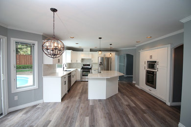 Photo of a large transitional u-shaped open plan kitchen in Vancouver with an undermount sink, shaker cabinets, white cabinets, quartzite benchtops, white splashback, stone slab splashback, stainless steel appliances, dark hardwood floors, with island, brown floor and white benchtop.