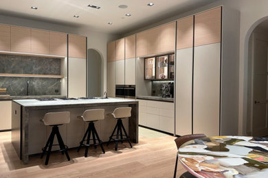 Diseño de cocina minimalista extra grande con armarios con paneles lisos, electrodomésticos con paneles, suelo de madera clara, suelo beige y encimeras verdes