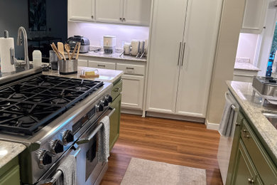 Kitchen pantry - large transitional u-shaped vinyl floor and brown floor kitchen pantry idea in Orange County with an undermount sink, recessed-panel cabinets, white cabinets, granite countertops, beige backsplash, granite backsplash, white appliances, two islands and beige countertops