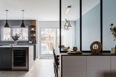 Inspiration for a large contemporary l-shaped eat-in kitchen in Montreal with an undermount sink, flat-panel cabinets, grey cabinets, quartz benchtops, grey splashback, ceramic splashback, stainless steel appliances, ceramic floors, with island, grey floor and grey benchtop.