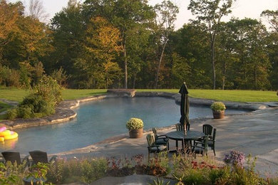 Large traditional backyard custom-shaped pool in New York with a hot tub and concrete pavers.