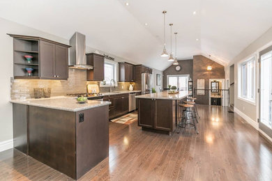 This is an example of a large contemporary l-shaped kitchen in Toronto with an undermount sink, shaker cabinets, dark wood cabinets, granite benchtops, beige splashback, glass tile splashback, stainless steel appliances, medium hardwood floors, with island and brown floor.