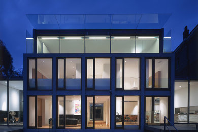 This is an example of a large contemporary three-storey glass grey exterior in London with a flat roof.