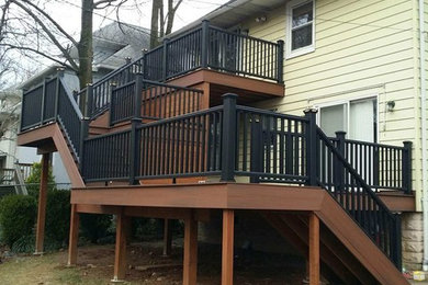 Huge mountain style backyard deck photo in New York with a roof extension