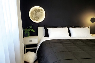 Diseño de dormitorio principal moderno de tamaño medio sin chimenea con paredes negras, suelo de madera clara y suelo beige
