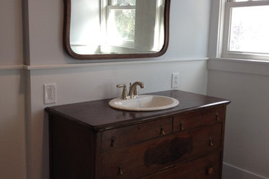 Inspiration for a mid-sized eclectic master ceramic tile and gray floor bathroom remodel in Other with furniture-like cabinets, medium tone wood cabinets, a one-piece toilet, gray walls, a drop-in sink and wood countertops