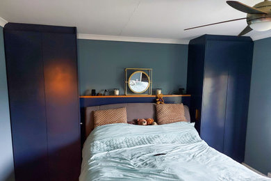 Small modern master bedroom in Surrey with blue walls and carpet.