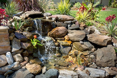 Photo of a mid-sized eclectic full sun front yard stone water fountain landscape in Other for fall.