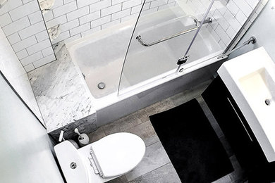 Example of a small transitional 3/4 gray tile and white tile bathroom design in Boston with flat-panel cabinets, dark wood cabinets, a two-piece toilet, gray walls, an integrated sink and a hinged shower door