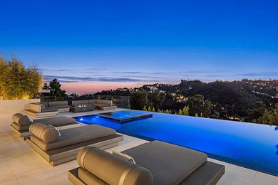 Inspiration for a large modern backyard stone and rectangular infinity hot tub remodel in Los Angeles