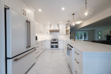 Mid-sized minimalist u-shaped porcelain tile and white floor open concept kitchen photo in Other with a farmhouse sink, shaker cabinets, white cabinets, quartz countertops, white backsplash, stone slab backsplash, white appliances, a peninsula and white countertops