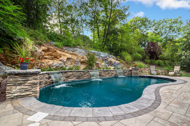 Traditional backyard kidney-shaped pool in New York with a water feature.
