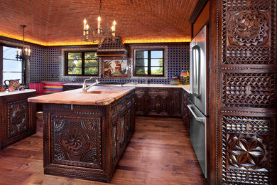 Large tuscan u-shaped medium tone wood floor eat-in kitchen photo in Santa Barbara with dark wood cabinets, multicolored backsplash, stainless steel appliances and an island