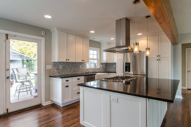 Photo of a mid-sized transitional l-shaped open plan kitchen in Seattle with a farmhouse sink, shaker cabinets, white cabinets, multi-coloured splashback, mosaic tile splashback, stainless steel appliances, medium hardwood floors and with island.