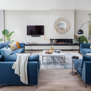 Medium sized beach style open plan games room in Dorset with white walls, light hardwood flooring, a ribbon fireplace, a freestanding tv and grey floors.