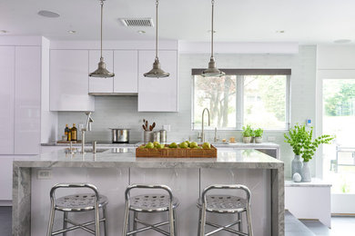 Example of a large trendy l-shaped eat-in kitchen design in New York with an undermount sink, flat-panel cabinets, white cabinets, white backsplash, glass tile backsplash, stainless steel appliances, an island and marble countertops