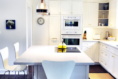 Example of a mid-sized transitional l-shaped dark wood floor enclosed kitchen design in Toronto with an undermount sink, shaker cabinets, white cabinets, quartz countertops, white backsplash, ceramic backsplash, paneled appliances and an island
