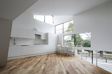 Design ideas for a small contemporary single-wall open plan kitchen in Osaka with flat-panel cabinets, white cabinets, solid surface benchtops, white splashback, medium hardwood floors, no island, white benchtop and wallpaper.