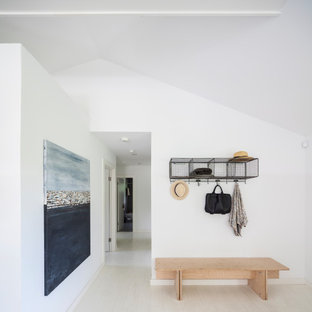 Minimalist light wood floor, beige floor and vaulted ceiling entryway photo in New York with white walls