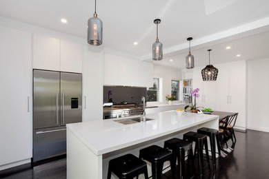 Inspiration for a large contemporary galley eat-in kitchen in Sydney with a double-bowl sink, flat-panel cabinets, white cabinets, laminate benchtops, black splashback, glass tile splashback, stainless steel appliances, dark hardwood floors and with island.