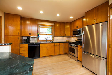 Inspiration for a mid-sized transitional l-shaped light wood floor enclosed kitchen remodel in Other with a double-bowl sink, shaker cabinets, medium tone wood cabinets, soapstone countertops, white backsplash, subway tile backsplash and stainless steel appliances