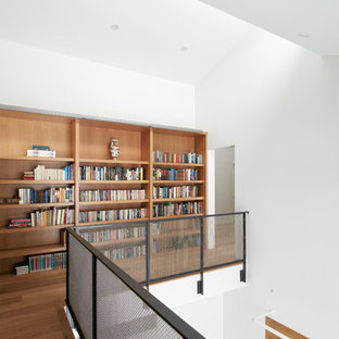 Immagine di un ampio studio moderno con libreria, pareti bianche, pavimento in cemento, nessun camino, scrivania incassata e pavimento grigio