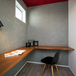 Photo of a modern home office and library in Other with grey walls, painted wood flooring, a built-in desk and grey floors.