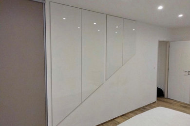 Exemple d'une armoire encastrée moderne de taille moyenne pour un homme avec des portes de placard blanches.
