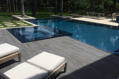 Large trendy backyard tile and custom-shaped infinity hot tub photo in Houston