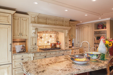 Example of a large classic l-shaped eat-in kitchen design in Los Angeles with a double-bowl sink, raised-panel cabinets, beige cabinets, granite countertops, beige backsplash, stone tile backsplash, stainless steel appliances and an island