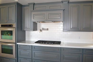 Large country single-wall light wood floor kitchen photo in Sacramento with a farmhouse sink, gray cabinets, quartz countertops, white backsplash, ceramic backsplash, stainless steel appliances and an island